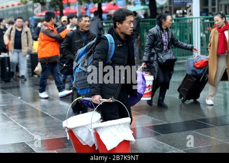 Passagiere tragen Plastikeimer, der ihr Gepäck enthält, und bereiten sich darauf vor, an Bord des Zuges zu gehen, der zu Hause am Shanghaier Bahnhof, Shanghai, China, ist. Stockfoto