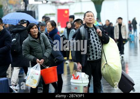 Passagiere tragen Plastikeimer, der ihr Gepäck enthält, und bereiten sich darauf vor, an Bord des Zuges zu gehen, der zu Hause am Shanghaier Bahnhof, Shanghai, China, ist. Stockfoto