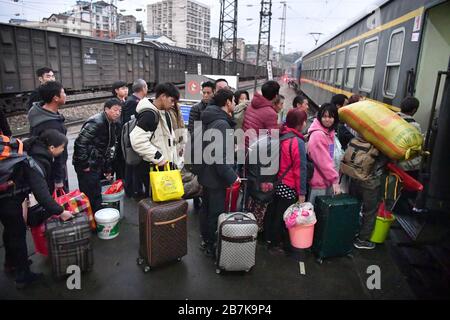 Die Passagiere tragen einen Plastikeimer, der ihr Gepäck enthält, und bereiten sich darauf vor, an Bord des Zuges zu gehen, der zu Hause am Bahnhof Huaihua, Stadt Huaihua, cen fährt Stockfoto