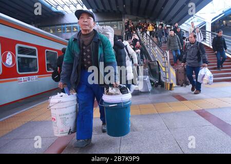 Passagiere tragen Plastikeimer, der ihr Gepäck enthält, und bereiten sich darauf vor, an Bord des Zuges zu gehen, der zu Hause am Bahnhof Beijingxi, Peking, China, fährt. Stockfoto
