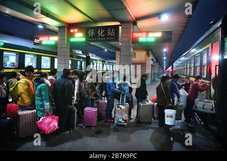 Die Passagiere tragen einen Plastikeimer, der ihr Gepäck enthält, und bereiten sich darauf vor, an Bord des Zuges zu gehen, der zu Hause am Bahnhof Huaihua, Stadt Huaihua, cen fährt Stockfoto