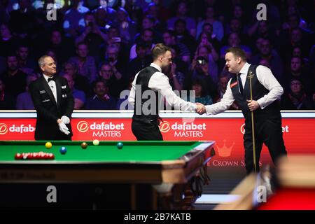 Judd Trump aus England, Middle, schüttelt mit Shaun Murphy aus England gleich beim Erstrundenspiel der Meister 2020 in London, dem United Kingdo, die Hände Stockfoto