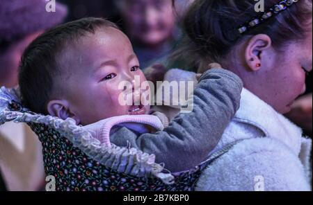 Mütter, die ihre Kinder auf dem Rücken und im Gepäck mitführen, warten auf den 3000 km entfernten Zug in Sichuan, der ihnen 36 Stück bringt Stockfoto