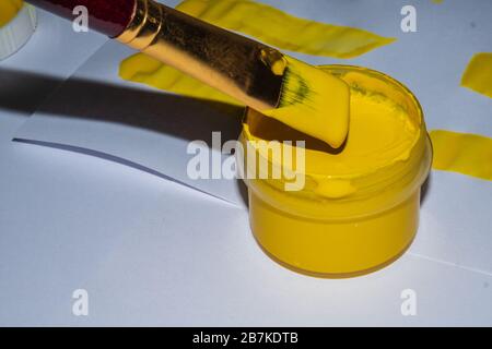 Foto einer Bürste und eines Röhrchens mit gelber Farbe. Stockfoto