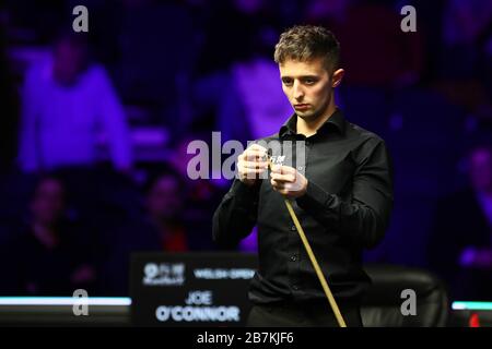 Der englische Snookerspieler Joe O'Connor chalcht seinen Cue, während er einen Schuss gegen den schottischen Profi-Snookerspieler John Higgins beim ersten rou in Erwägung zieht Stockfoto