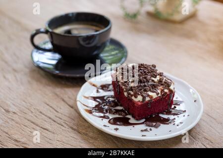 Ein Stück roter Samtkuchen mit Kaffeetasse auf Holztisch im Café Stockfoto