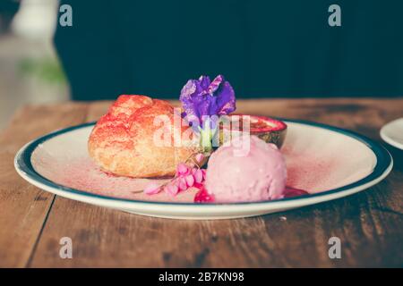 Nahaufnahme eines Gerichts aus Choux Sahne, Rosen-Eis und Passionsfrucht mit schöner Dekoration Stockfoto