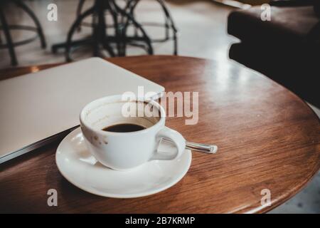 Closeup Bild der Farbe silber Laptop und Kaffee Tasse auf Holztisch mit blur cafe Hintergrund Stockfoto