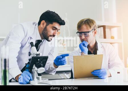 Das Forschungsteam der Wissenschaftler führt gemeinsam Experimente durch und untersucht das Mikroskop in modernen Labors/Wissenschaftlern der Biochemie-Genetik im Labor Stockfoto