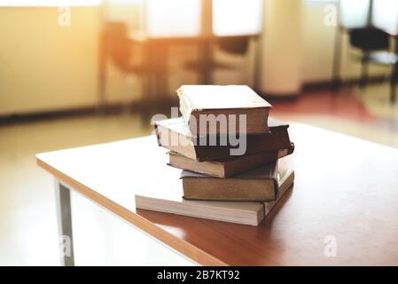 Bücher auf dem Tisch in der Bibliothek / Bildung Lernbuch Stapel auf Holztisch und verschwommener Raumhintergrund, zurück zum Schulkonzept Stockfoto