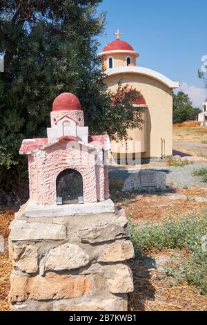 Farbenfroher Schrein Proskinitari mit der kleinen privaten Kirche auf dem Hintergrund im Dorf Kolossi. Limassol District. Zypern Stockfoto