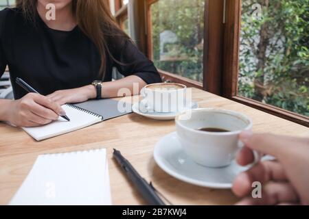 Nahaufnahme von zwei Geschäftsleuten, die Kaffee trinken, während sie im Büro sprechen und sich treffen Stockfoto