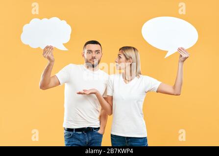 Emotionale Frau und Mann, die Papier halten, überblasen den gelben Hintergrund. Beziehungskonzept Stockfoto