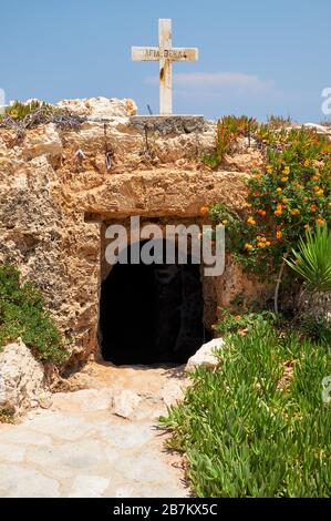 Die kleine Katakombenkirche von Ayia Thekla (Agia Thekla), in den Felsen an der Küste gehauen und das Steinkreuz auf dem Felsvorsprung darüber. Ayia Napa. Zyp Stockfoto