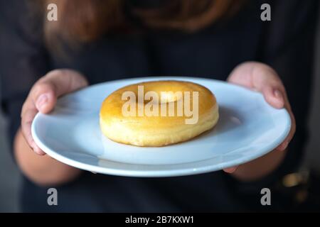 Eine Frau, die einen Donut-Teller hält und zeigt Stockfoto
