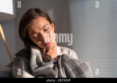 Coronavirus Disease (COVID-19) Symptome sind eine laufende Nase, Halsschmerzen, Husten und Fieber. Corona-Viruserkrankung kann für manche Menschen schwerer sein. Asian Woman mit Kehlschmerzen zu Hause. Stockfoto