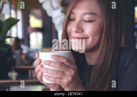 Closeup Bild der asiatischen Frau riechen und trinken heißen Kaffee mit einem guten Gefühl im Cafe Stockfoto