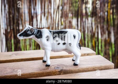 Nahaufnahme einer Plastikspielzeug-Kuh auf einem Holz Oberfläche Stockfoto