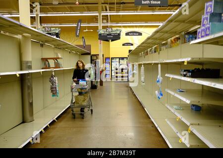 Bloomington, Vereinigte Staaten. März 2020. Eine Frau läuft an einem leeren Papiertuch vorbei, und toilettenpapierregale, Käufer füllen einen Kroger Laden, um Lebensmittel bei Panikkäufern zu kaufen, haben aufgrund der Coronavirus Pandemie in Bloomington täglich Regale freigemacht. Credit: SOPA Images Limited/Alamy Live News Stockfoto