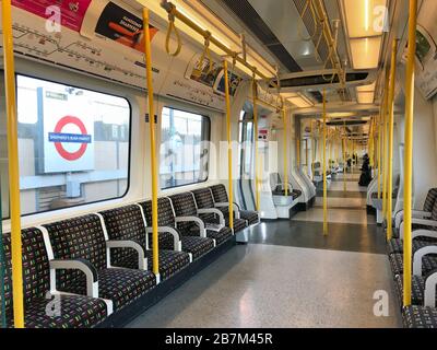 Eine spärlich besetzte Kutsche in einem U-Bahn-Zug im Westen Londons am Tag, nachdem Premierminister Boris Johnson die Menschen dazu aufforderte, sich von Kneipen, Clubs und Theatern fernzuhalten, möglichst von zu Hause aus zu arbeiten und alle nicht notwendigen Kontakte zu vermeiden und zu reisen, um die Auswirkungen der Coronavirus Pandemie zu verringern. Stockfoto