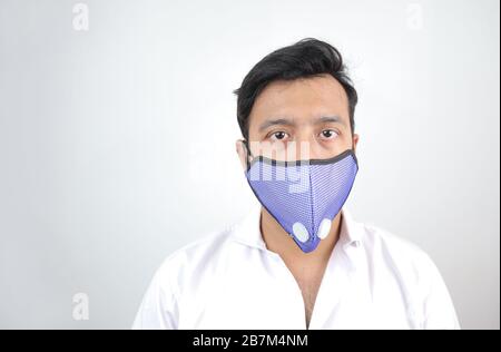 Ein männlicher Arzt, der eine Maske mit Platz für Text in einem verlaufenweißen Hintergrund trägt. Stockfoto