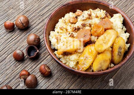 Hirseporridge mit karamellisierten Bananen und Nüssen. Stockfoto