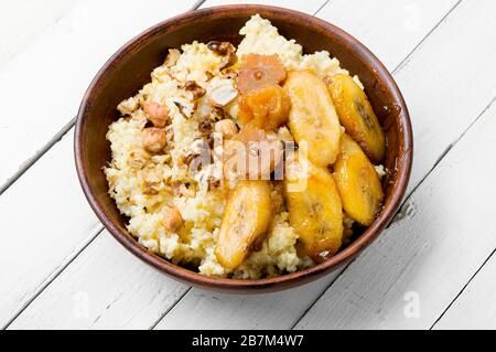 Hirseporridge mit karamellisierten Bananen und Nüssen. Stockfoto