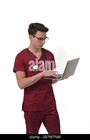Junger männlicher Arzt mit Stethoskop über dem Hals Arbeiten am Laptop, isoliert auf weiß Stockfoto