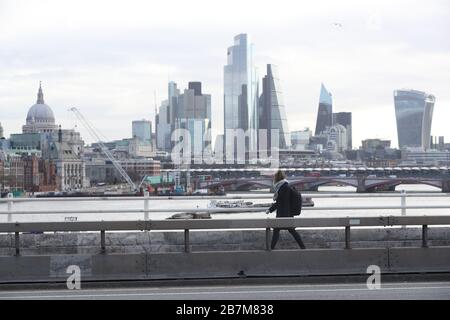 Ein Pendler überquert in London eine leere Waterloo-Brücke, am Tag nachdem Premierminister Boris Johnson die Menschen dazu aufforderte, sich von Kneipen, Clubs und Theatern fernzuhalten, möglichst von zu Hause aus zu arbeiten und alle nicht notwendigen Kontakte zu vermeiden und zu reisen, um die Auswirkungen der Coronavirus Pandemie zu verringern. Stockfoto