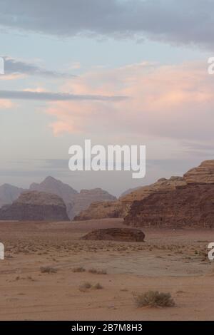 Porträtfoto von Wadi Rum nach Sonnenuntergang mit rosa Wolken Stockfoto