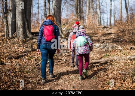 Familienporträt auf Waldreise mit Wanderkleidung. Winterporträt der Familie auf Familienwanderung in Wald, aktive Familie, Eltern und Kinder Stockfoto