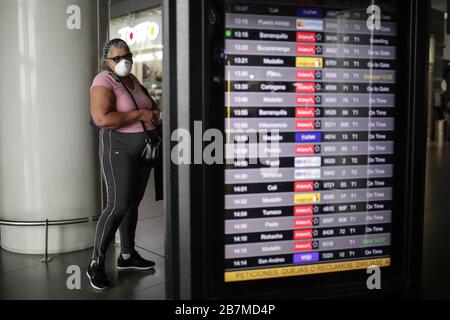 Bogota, Kolumbien. März 2020. Eine Frau, die Maske trägt, überprüft die Fluginformationen auf dem internationalen Flughafen El Dorado in Bogota, Kolumbien, am 16. März 2020. In Kolumbiens Hauptstadt Bogota hat Bürgermeisterin Claudia Lopez einen Unglückszustand ausgerufen, um in den kommenden Tagen mehr Stadtbudgets für einen möglichen Gesundheitsnotstand zuzuweisen. Kolumbien hat 54 bestätigte Fälle gemeldet, darunter 28 in Bogota. Die kolumbianische Regierung hat die Schließung von Bars, Nachtclubs und Diskotheken angeordnet und Versammlungen von mehr als 50 Personen verboten. Credit: Jhon Paz/Xinhua/Alamy Live News Stockfoto