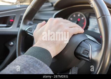 Ein Mann in einem modernen Auto. Hand drückt den Signalton und gibt ein Signal aus. Nahaufnahme. Stockfoto