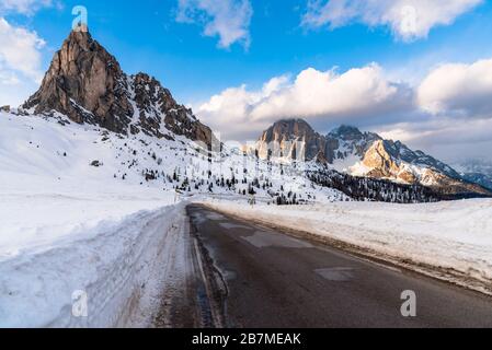 Leere Straße in einer majestätischen verschneiten Bergkulisse in den Alpen am klaren Wintertag Stockfoto