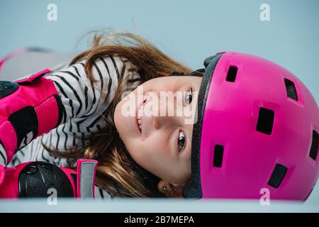 Porträt des Vorschoolers in pinkfarbenem Helm auf dem Boden Stockfoto