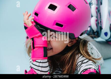 Porträt eines lustigen Mädchens von Vorschoolerin in pinkfarbenem Helm auf dem Boden liegend Stockfoto