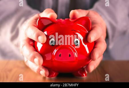 Die Hände schließen schützend eine rote Ferkelbank Stockfoto