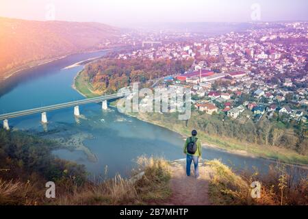 Ein Mann steht auf einem Hügel und blickt auf einen fantastischen Blick auf den gewundenen Dniester River im Morgengrauen des Herbstes. Dniester Canyon National Park, Zalischchyky Tow Stockfoto