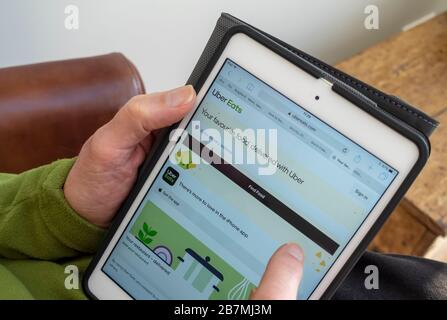 Nahaufnahme der Person Mann suchen und online bestellen von Uber Eats Takeaway Website auf iPad Tablet England Großbritannien GB Großbritannien Stockfoto