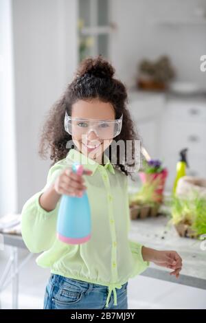 Lustige Mädchen in einer Brille mit einem Wasserspray in der Hand. Stockfoto