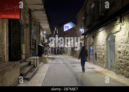 Einsamer Fußgänger spaziert durch die verlassene Rivlin Street in Nahalat Shiva eine meist überfüllte Fußgängerpromenade mit Straßencafés und Bars inmitten der Coronavirus (COVID-19) Pandemie, West Jerusalem Israel Stockfoto