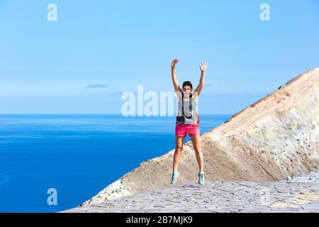 Frau, die Yoga praktiziert und auf den Felsen von Vulcano Island, Äolischen Inseln, Italien springt. Mittelmeer im Hintergrund. Stockfoto