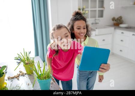 Zwei fröhliche Freundinnen fotografieren sich zu Hause auf einem Tablet. Stockfoto
