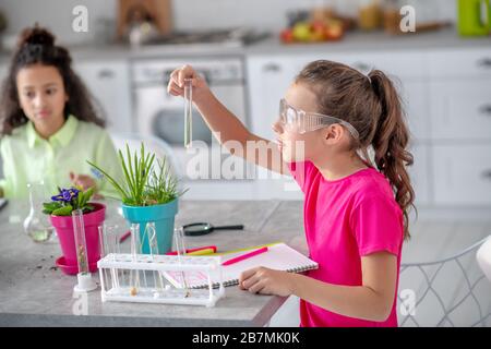 Mädchen in einer Schutzbrille mit einem Reagenzglas in der Hand. Stockfoto