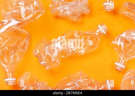 Viele gebrauchte Plastikflaschen auf orangefarbenem Hintergrund. Das Konzept der Verschmutzung des Planeten und der Ozeane durch Plastikmüll. Stockfoto