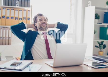 Nahaufnahme des erfolgreichen Geschäftsmannes, der in seinem Büro ruht. Er hat einen tollen Job gemacht, ist also zufrieden und macht Pause, um sich zu entspannen Stockfoto