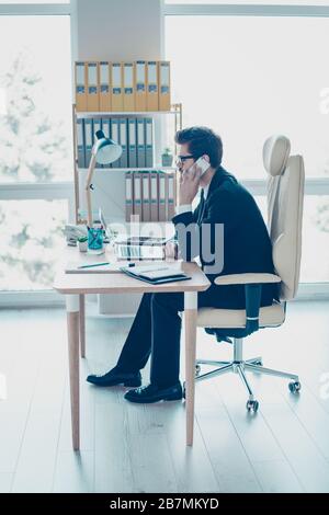 Vertikales Foto eines erfolgreichen jungen Arbeitgebers, der mit dem Kunden im Büro auf dem Smartphone spricht Stockfoto