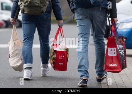 17. März 2020, Sachsen, Dresden: Zwei Männer tragen gefüllte Einkaufstaschen über einen Parkplatz. Foto: Sebastian Kahnert / dpa-Zentralbild / dpa Stockfoto