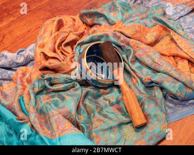 Haulerwijk - 07. märz 2020: Haulerwijk, Niederlande. Blaue und goldene Gesangsschüssel aus sieben Metallen mit einem Holzstreifer auf einem indischen Schal Stockfoto