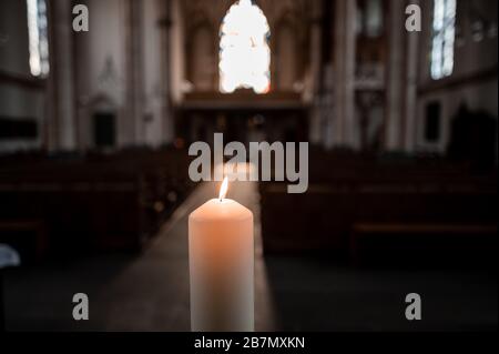 Oberhausens, Deutschland. März 2020. In der leeren Kirche brennt eine Kerze. Ein katholischer Priester aus dem Ruhrgebiet hat mit einer ungewöhnlichen Aktion auf das Verbot der Gottesdienste aufgrund der Korona-Epidemie reagiert. Christoph Wichmann von der Pfarrgemeinde St. Pankratius in Oberhausens rief auf der Webseite der Kirchengemeinde an, abends um 19 Uhr eine Kerze anzuzünden, sie auf die Fensterbank zu stellen und dann das Vaterunser zu beten. Kredit: Fabian Strauch / dpa / Alamy Live News Stockfoto